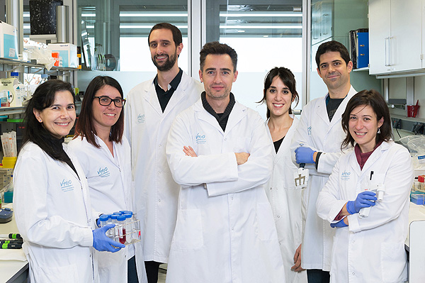 El doctor Palmer (en el centro con los brazos cruzados) y la doctora Puig (a la izquierda con guantes y material de laboratorio), junto a investigadores que han participado en el estudio Fuente: Vall d’Hebron / VHIO / Galènia
