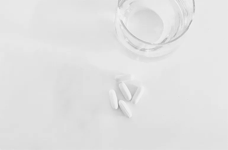 (portada 2) vaso de agua con pastillas blancas comprimidos cápsulas